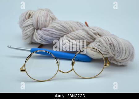 Matassa o palla di filato o lana tinta a mano con fiocco di fiocco e un paio di occhiali da lettura Grandma con rifilatura d'oro retrò Foto Stock