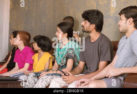 Gruppo di fratelli e sorelle di famiglia che guardano la tv sul divano a casa - concetto di legame familiare, di togetherness, di intrattenimento nel fine settimana e di socializzazione Foto Stock