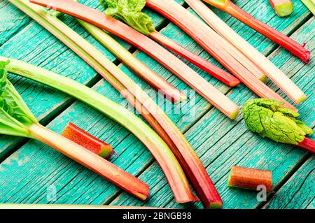 Rhubarb fresco stelo su retro tavola di legno. Pacchetto di steli e pezzi rabarbaro Foto Stock