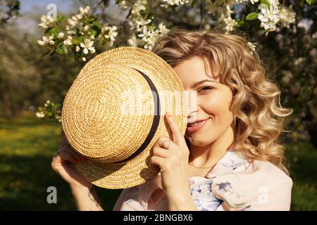 Donna coperta metà del viso con un cappello di paglia - tempo felice nel giardino verde - primavera e estate Foto Stock