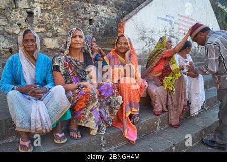 Le donne di una famiglia indù, nel sacro punto indù Banganga Tank, Walkeshwar, Mumbai, India, la donna sulla destra benedicendo un parente più giovane Foto Stock