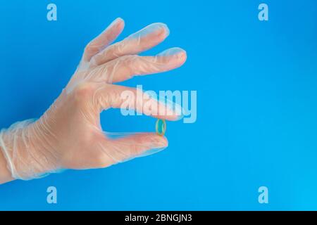 La mano del medico nel guanto medico contiene la capsula gialla dell'olio di pesce. Prevenzione della felicite della vitamina D con spazio di copia Foto Stock