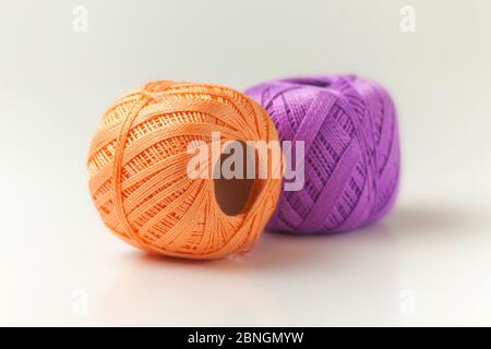 Due matasse di filo in viola e arancione. Lavorazione a maglia su sfondo bianco. Hobby. Foto Stock