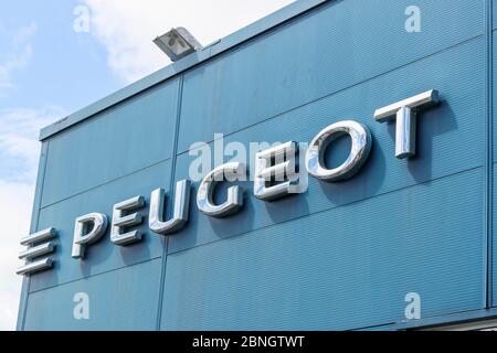 Logo del marchio aziendale per i veicoli Peugeot, segno sul lato di un garage di vendita, Ayr, Regno Unito Foto Stock