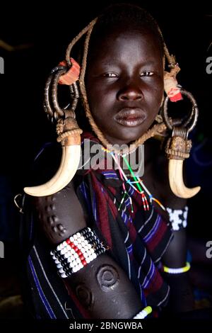 Giovane ragazza con scarificazione vestendo abiti tradizionali. Tribù di Mursi, Parco Nazionale di Mago. Valle di Omo, Etiopia. Foto Stock