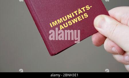 passaporto o tessera d'immunità tedesca - primo piano mano che tiene mock-up certificato immunitario europeo documento di viaggio Foto Stock
