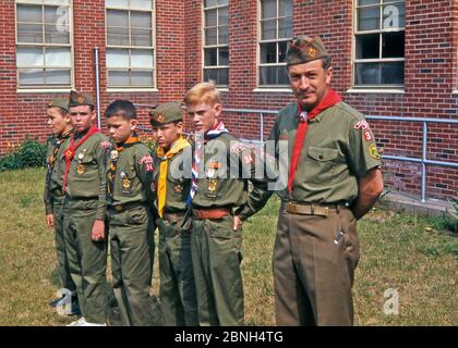 I ragazzi scout e il loro leader (Akela) dal Pearl River dalla truppa numero 34 (o pacchetto), Pearl River, New York, Stati Uniti a metà degli anni '60. I ragazzi mostrano i numerosi badge che hanno vinto e indossano i loro distintivi fazzoletti e slide. Il leader ha un insolita diapositiva – un nativo americano in un headdress – mentre il ragazzo medio ha uno scivolo del cranio. Foto Stock