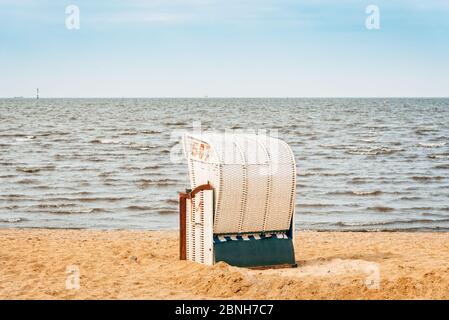 Spiaggia sabbiosa e tipiche sedie a sdraio con cappuccio a Cuxhaven, sulla costa del Mare del Nord, una giornata nuvolosa d'estate. Germania Foto Stock