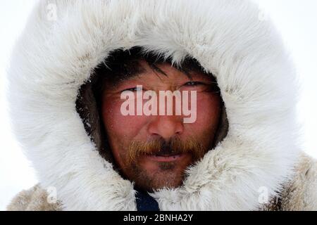 Sergueï Chorolya, mandria di renne Nenet, vestito con un caldo cappotto di pelliccia di renna. Distretto di Yar-sale, Yamal, Siberia nord-occidentale, Russia. Aprile 2016. Foto Stock