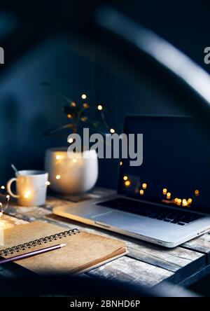 Accogliente spazio di lavoro con computer portatile, nota con matita e tazza di caffè, piante e giallo brillante sfondo grigio pietra di Garlandat parete. Lavorare da casa conc Foto Stock
