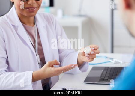 Primo piano di donne dottore che tengono pillole in mano e prescriverle al paziente Foto Stock