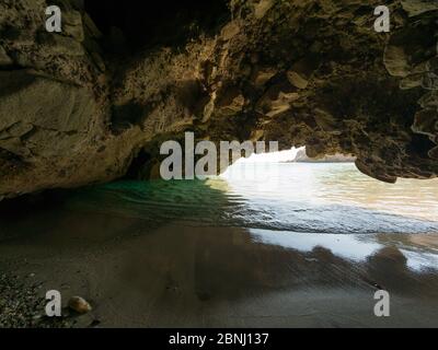 Piccola grotta sulla spiaggia di Tsigrado con acque cristalline dell'isola di Milos, Grecia Foto Stock