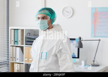 Medico di sesso maschile indossando indumenti protettivi in piedi in ospedale Foto Stock