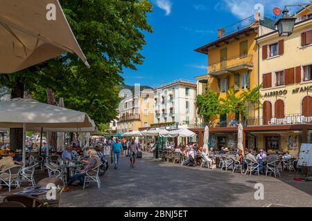 Vista di caffè e visitatori sul lungomare in una giornata di sole, Garda, Lago di Garda, Provincia di Verona, Veneto, Laghi Italiani, Italia, Europa Foto Stock