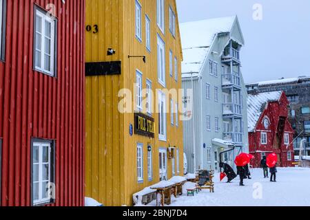 Turisti, edifici storici colorati in legno, neve pesante in inverno, Tromso, Troms og Finnmark, Circolo polare Artico, Norvegia del Nord, Scandinavia, Europa Foto Stock