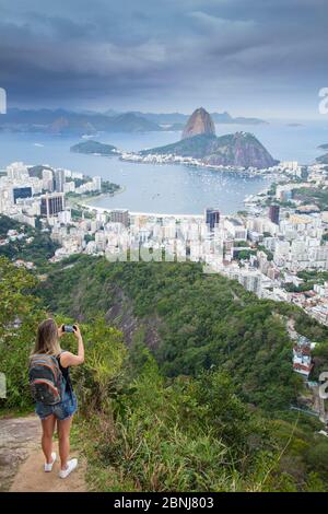 Una donna escursionista che guarda fuori sul paesaggio di Rio a Sugar Loaf montagna dal Parco Nazionale Tijuca, Rio de Janeiro, Brasile, Sud America Foto Stock