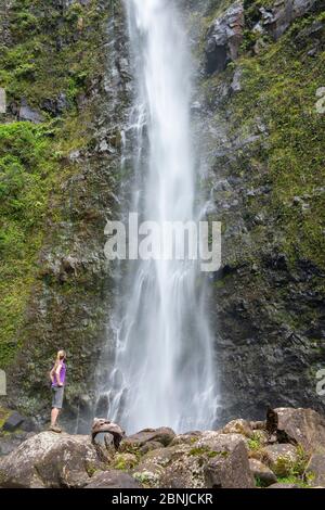 Escursionista ammirando una cascata lungo il famoso Kalalau Trail, lungo la costa Na Pali di Kauai, Kauai, Hawaii, Stati Uniti d'America, Nord America Foto Stock