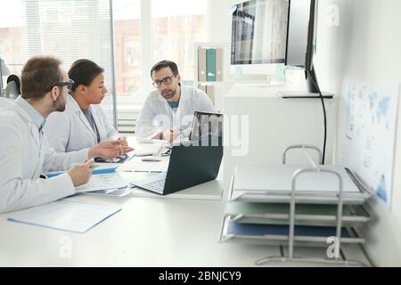 Gruppo di medici seduti al tavolo e discutere insieme i problemi durante una riunione di lavoro in ufficio Foto Stock