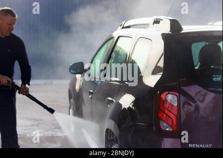 Un uomo lava un'auto in un autolavaggio senza contatto, un uomo lava un'auto marrone, Kaliningrad, Russia, 1 marzo 2020 Foto Stock