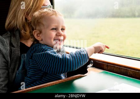 Due anni ragazzo e madre in vecchio treno a vapore carrozza che indica fuori dalla finestra, Bluebell Railway, Sussex, Inghilterra, Regno Unito, Europa Foto Stock