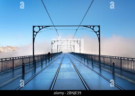 Tram tracce nella nebbia di prima mattina che corre sul ponte Dom Luis i a Porto, Portogallo, Europa Foto Stock