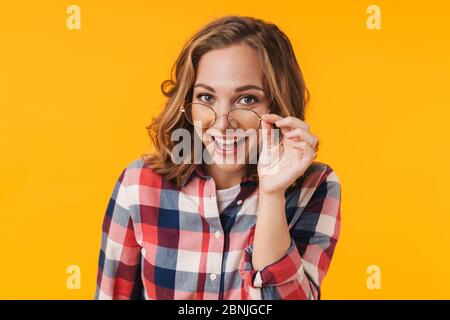 Immagine di giovane bella donna che indossa occhiali e camicia plaid sorridente isolato su sfondo giallo Foto Stock