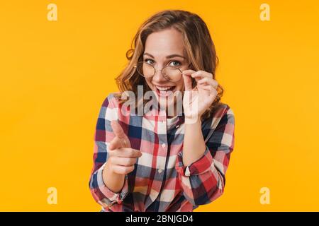 Immagine di giovane bella donna che indossa camicia plaid sorridente e puntando il dito verso di voi isolato su sfondo giallo Foto Stock