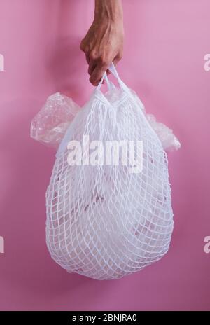 Sacchetti di plastica in una borsa a corda su sfondo rosa. Foto Stock