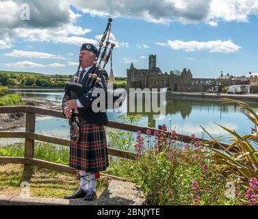 Timoleague, West Cork, Ireland. 15th May, 2020. Local man Michael Heaney from Timoleague plays the bagpipes with Timoleague Abbey in the background. Mr Heaney was filmed playing the pipes as part of Arigideen Rangers GAA Club's fundraising initiative. The GAA Club is raising money for Clonakilty Community Hospital, Pieta House and Timoleague Parish Church. Credit: AG News/Alamy Live News Foto Stock