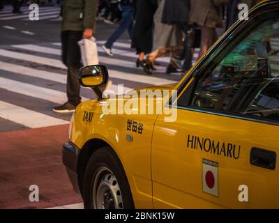 Shibuya, Giappone - 7.2.20: Una cabina gialla tirata in su davanti al famoso incrocio di scrambling di Shibuya. Foto Stock