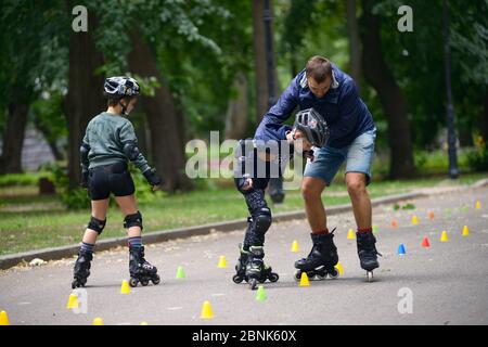 Rollerblading. L'allenatore corregge i movimenti del ragazzo insegnando lo slalom artistico Foto Stock