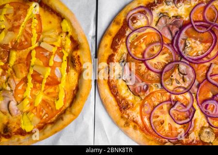 due pizze con carne, funghi, ananas, pomodoro, cipolla. Pasticceria tradizionale per la festa, fuoco selettivo Foto Stock