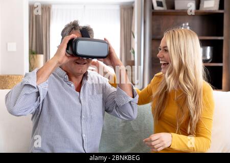 Uomo caucasico senior e sua figlia adulta che usano un visore VR a casa Foto Stock