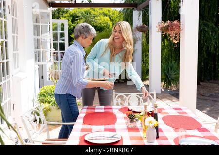 Due donne caucasiche preparano un pranzo in giardino Foto Stock