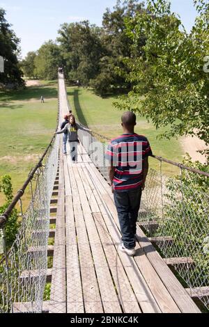 Apache Pass Texas USA, ottobre 2012: La sedia a rotelle Junior High studentin attraversa un ponte oscillante sul fiume San Gabriel nel Texas centrale durante una gita sul campo per assistere alla presentazione del primo cartello stradale lungo la parte Texas del El Camino Real del los Tejas National Historic Trail presso l'Apache Pass. ©Bob Daemmrich Foto Stock