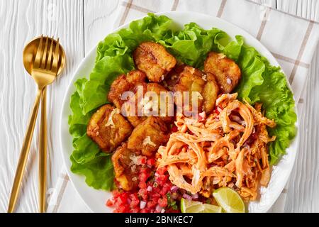 Cucina latino-americana: Platani verdi fritti con aglio serviti con pollo sminuzzato caricato con salsa di bufalo e pico de gallo con lime o Foto Stock