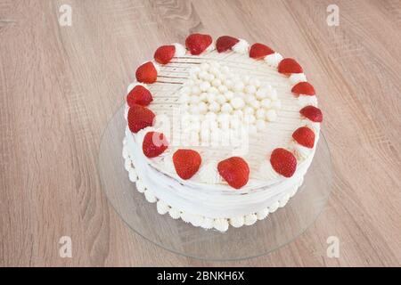 Torta fatta in casa per la giornata della madre decorata con fragole e ciuffi di panna montata sotto forma di cuore Foto Stock