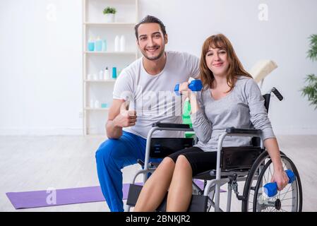 Donna in sedia a rotelle facendo esercizi sportivi con allenatore personale Foto Stock