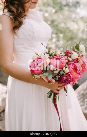 Primo piano bouquet sposa, il bouquet è composto da peonie rosse, rose rosse e bianche. La sposa tiene il bouquet Foto Stock