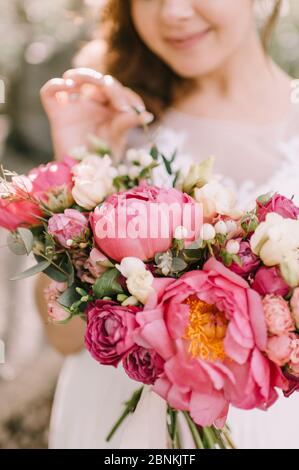 Primo piano bouquet sposa, il bouquet è composto da peonie rosse, rose rosse e bianche. La sposa tiene il bouquet Foto Stock