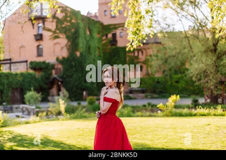 Bella donna tattoed rosso in abito rosso che posa vicino al castello Foto Stock