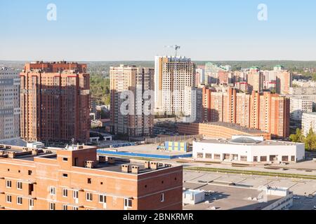 Un nuovo quartiere adatto alle famiglie con alti edifici in mattoni marroni e un grande garage con parcheggio multilivello, un progetto di costruzione che si incontra Foto Stock