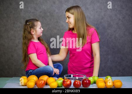 Bambina con mamma gioca con frutta e sorridente. Vitamine e nutrizione sana per i bambini. Foto Stock