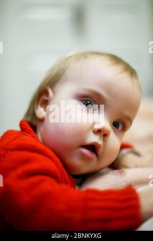 bambina in un maglione rosso, il suo viso è sporco di cibo, bella bokeh Foto Stock