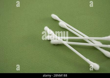 Auricolari in cotone di plastica su sfondo verde. Modello di intestazione con spazio di copia. Bastoncini di cotone organici per l'igiene personale. Concetto di cura dell'orecchio f Foto Stock