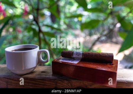 America, Caraibi, grandi Antille, Repubblica Dominicana, Jarabacoa, Los Calabazos, Sonido del Yaque Eco Lodge, caffè e sigaro su una ringhiera terrazza Foto Stock