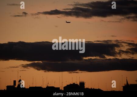 Aereo al tramonto che attraversa le nuvole della città. Silhouette cittadine Foto Stock