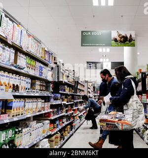 Acquirenti in un supermercato indossare maschere facciali di protezione e osservare la distanza sociale durante il Pandemic di Coronavirus Foto Stock