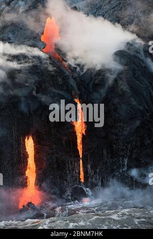 La lava calda proveniente dal flusso 61G, che emana da pu'u o'o sul vulcano Kilauea, scorre sulle scogliere del mare e nell'oceano attraverso i tubi di lava al Kamokuna oc Foto Stock