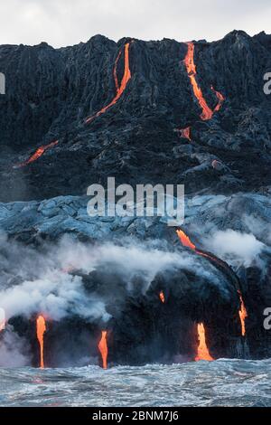 La lava calda del flusso 61G, che emana da pu'uu o'o sul vulcano Kilauea, scorre sopra le scogliere del mare e nell'oceano attraverso i tubi di lava al Kamokuna o Foto Stock